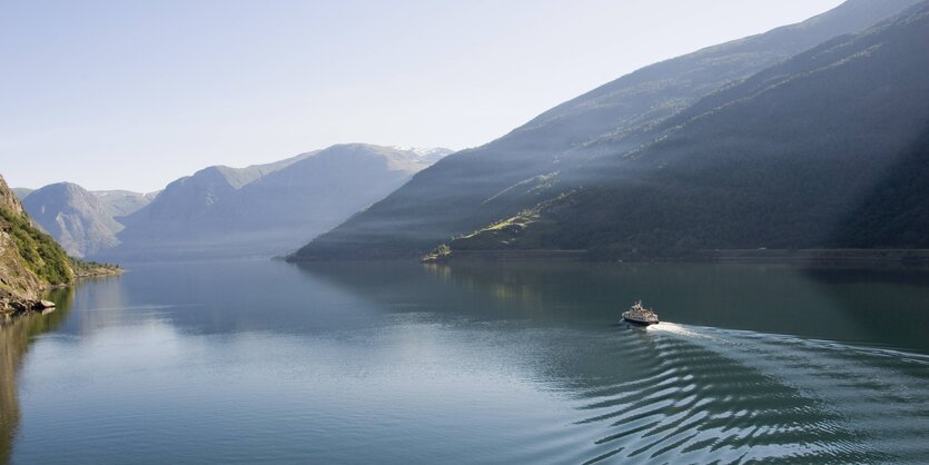 Ein norwegischer Fjord, in der Mitte des Gewässers ein Schiff