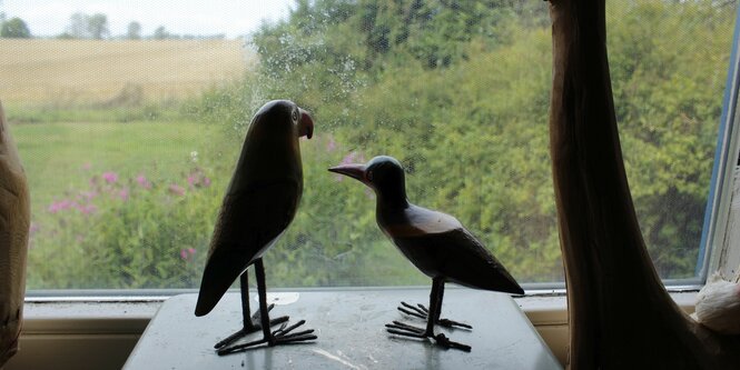 Zwei Vogelstatuen stehen vor dem Fenster