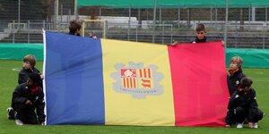 Kinder mit der Fahne Andorras aus einem Fußballplatz