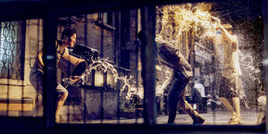 Szene aus "Parasite". Zwei Männer und ein Junge machen eine Wasserschlacht im Dunkeln.