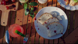 Ein Frühstückstisch. Darauf stehen Trauben und Saft und ein Teller mit einer Scheibe Toastbrot. Es ist mit roten Klecksen übersäht.