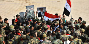 Eine große Gruppe von Soldaten hält Flaggen und Plakate in die Höhe.