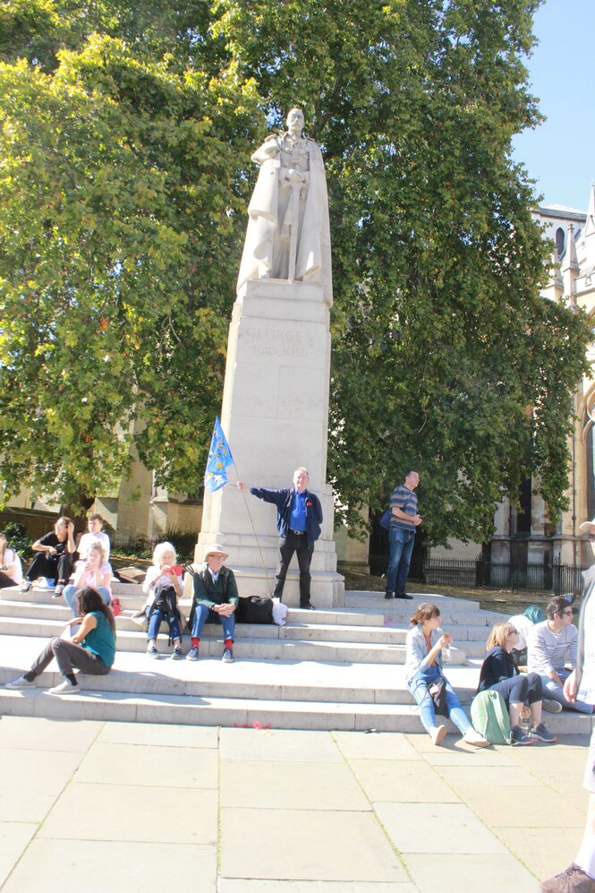 ein Mann steht vor einem Denkmal und schwingt eine Fahne