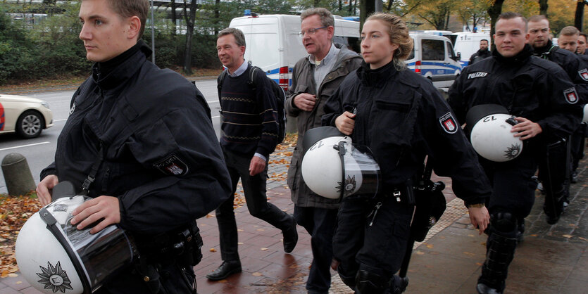 Bernd Lucke läuft unter Polizeischutz eine Straße entlang