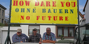 Bauern stehen unter einem Schild mit der Aufschrift "How dare you - ohne Bauern - no future".