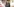 Eine junge Frau in Lederjacke steht vor einer besprayten Wand und lächelt