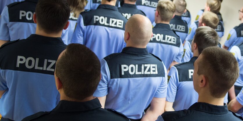 Polizisten stehen in Reihen und sind nur von hinten zu sehen