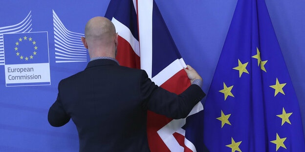 EIn Mann richtet die britische neben der EU-Fahne
