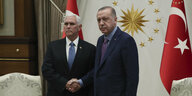 Zwei Männer vor türkisichen Fahnen reichen sich die Hand