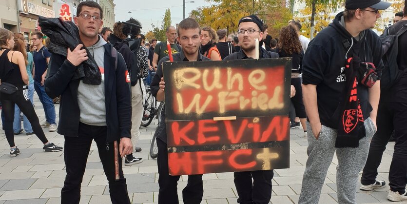 Vier Männer tragen ein Schild, auf dem steht: „Ruhe in Frie. Kevin HFC"