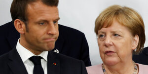 Emmanuel Macron und Angela Merkel im Porträt, sie gucken beide nicht glücklich