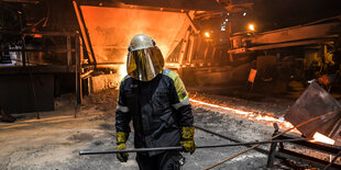 ein Arbeiter im Schutzanzug vor einem Hochofen