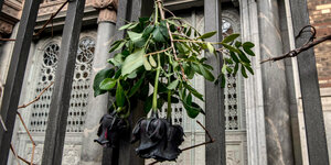 Schwarze Rosen an einem Eisengitter vor einer Synagoge