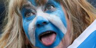Gesicht mit der schottischen Flagge bemalt - Der Mensch streckt seine Zunge raus