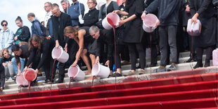 Menschen kippen eimerweise Kunstblut auf eine Treppe