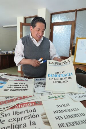 Ein Mann zeigt die Titelseite einer Zeitung, die auf die Bedrohung der Meinungsfreiheit in Ecuador hinweist