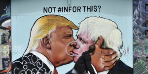 Ein Radfahrer betrachtet ein gemaltes Bild, das Donald Trump und Boris Johnson küssend zeigt