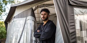 Ein Mann steht vor einem Zelt