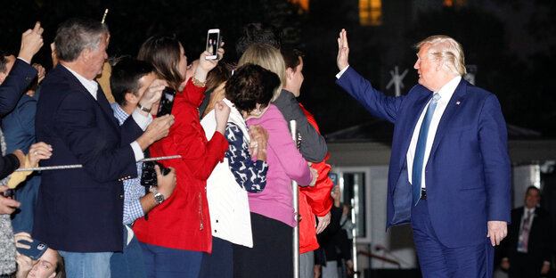 Donald Trump winkt begeisterten Menschen zu, die ihn fotografieren.