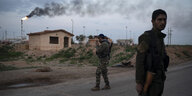 Im Vordergrung SDF-Kämpfer, im Hintergrund eine brennende Fackel in einem Ölfeld.