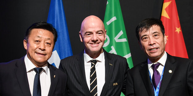 Gianni Infantino mit Partnern vom chinesischen Fußballverband, im Hintergrund Fahnen.