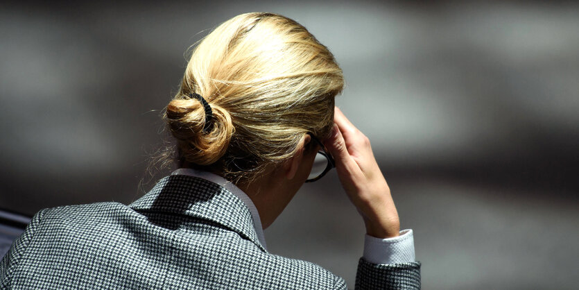 Alice Weidel wendet sich von der Kamera ab und fasst sich an die Stirn.