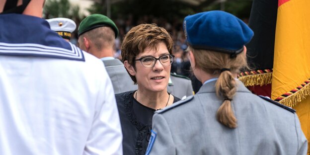 Kramp-Karrenbauer steht zwischen mänlichen und weiblichen Soldaten bei einem Gelöbnis in Berlin.