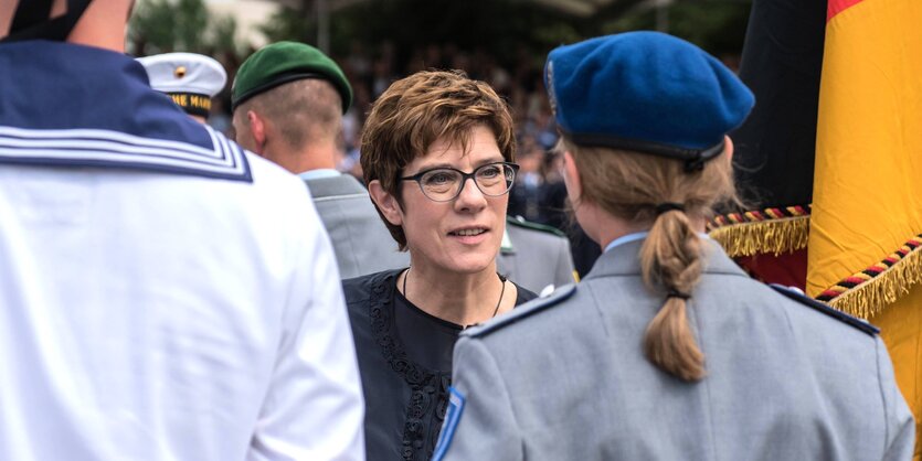 Kramp-Karrenbauer steht zwischen mänlichen und weiblichen Soldaten bei einem Gelöbnis in Berlin.