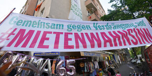 Menschen stehen unter einem Banner bei einem Protest gegen Verdrängung