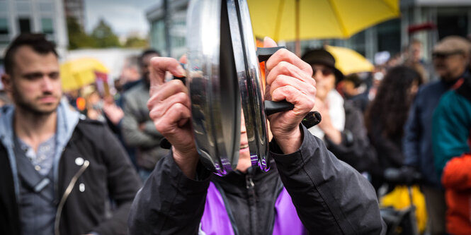 Ein Demonstrant schlägt zwei Topfdeckel aneinander