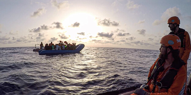 Seenotretter vom Rettungsschiff «Alan Kurdi» die zu einem Schlauchboot voller Flüchtlinge schauen