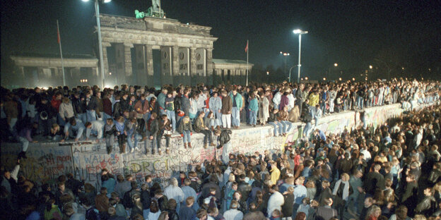 Menschen feiern vor 30 Jahren auf der Mauer deren Fall