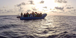 Ein Schlauchboot auf dem Meer. Im Hintergrund geht die Sonne unter