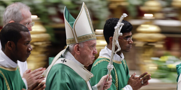 Der Papst läuft in Begleitung betender Männer in den Petersdom.