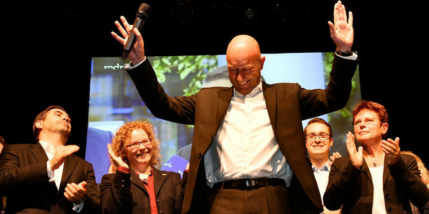 Thomas Kemmerich streckt dankend beide Arme aus, um ihn herum stehen Parteimitglieder und applaudieren