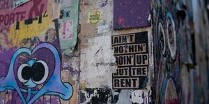 Eine bunt bemalte Hauswand auf der steht "ain't nothing going up but the rent"