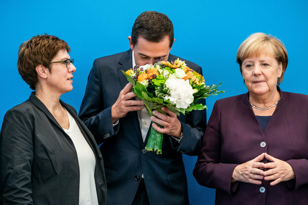 Mike Mohring riecht an einem Strauß Schnittblumen. Neben ihm stehen rechts und links, Angela Merkel und Annegret Kramp-Karrenbauer