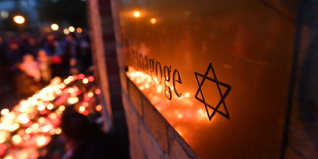 Ein Meer aus Kerzen spiegelt sich in der Fassade der Synagoge von Halle