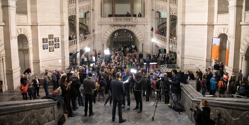 Pressevertreter im mehrstöckigen Foyer eines Rathauses