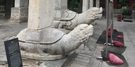 Zwei Steinstatuen von Schildkröten mit Drachenköpfen, die etwas auf dem Rücken tragen