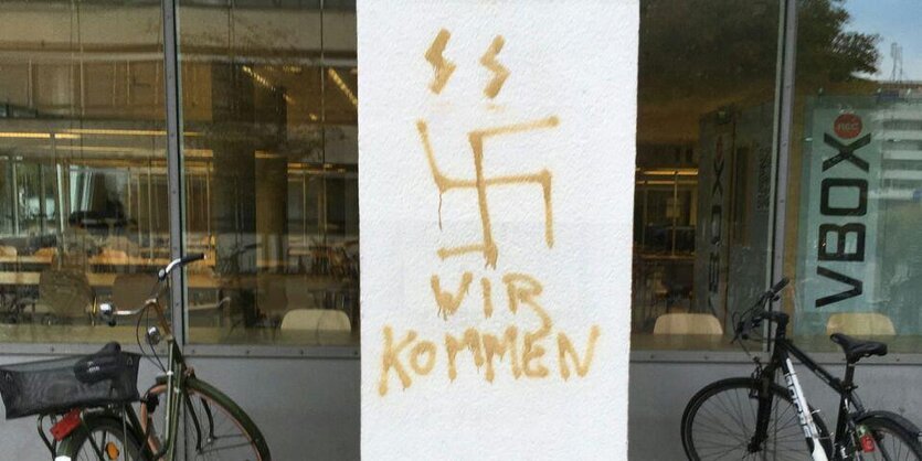 Eine Säule, beschmiert mit SS-Runen, einem Hakenkreuz und den Worten "Wir kommen".