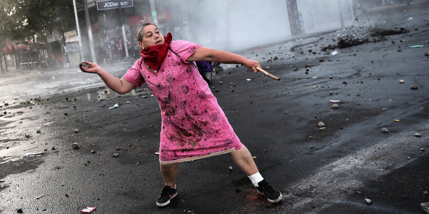 Frau in rosa Kleid wirft einen Stein