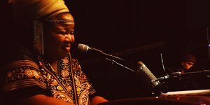 Schwarze Frau in traditioneller akfrikanischer Kleidung am Mikrofon