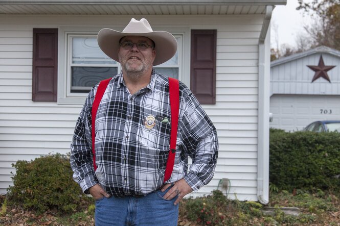 Mann mit Cowboyhut vor einem Holzhaus