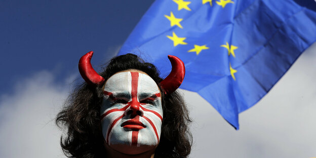 Anti-Brexit Demonstrant mit Gesichtsbemalung der britischen Flagge vor einer EU-Fahne