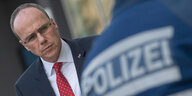 Hessens Innenminister Peter Beuth (CDU) schaut auf einen Polizisten