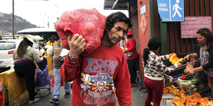 Mann trägt einen Sack Gemüse auf der Schulter auf dem Markt in Santiago