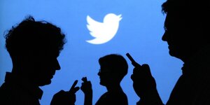 Twitter-Werbung-mit Menschen die auf ihre Smartphones starren mit Twitterlogo im Hintergrund