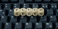 Buchstabenwürfel auf einer Tastatur zeigen die Worte „Fluch“ und „Segen“