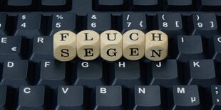 Buchstabenwürfel auf einer Tastatur zeigen die Worte „Fluch“ und „Segen“